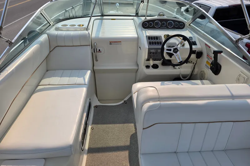 Slide: The Image of 1997 Sea Ray 250 Sundancer boat interior with white seating and steering console. - 8