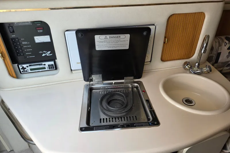 Slide: The Image of 1997 Sea Ray 250 Sundancer galley with stove, sink, and control panel. - 18