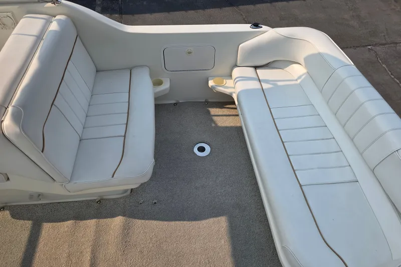 Slide: The Image of Interior seating of a 1997 Sea Ray 250 Sundancer boat, featuring white cushioned benches. - 7