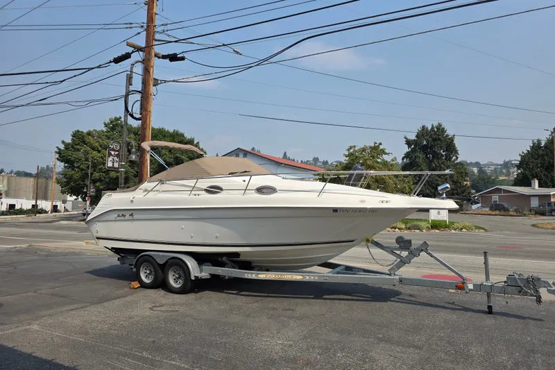 The Image of 1997 Sea Ray 250 Sundancer boat on trailer, parked on street, clear day. - 0