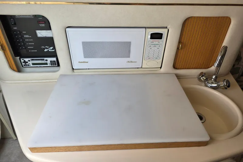 Slide: The Image of 1997 Sea Ray 250 Sundancer galley with microwave, sink, and control panel. - 16