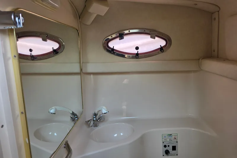 Slide: The Image of 1997 Sea Ray 250 Sundancer bathroom interior with sink, mirror, and porthole window. - 14