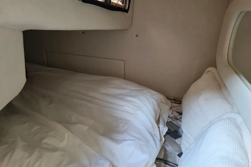 Slide: The Image of 1997 Sea Ray 250 Sundancer cabin interior with cozy bedding and soft lighting. - 22