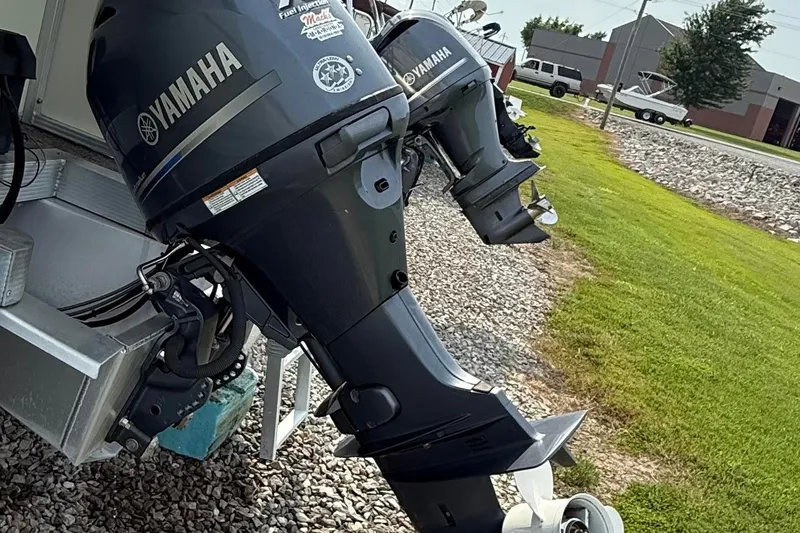 Slide: The Image of Twin Yamaha outboard motors on a 2005 Avalon Paradise Elite 2425 boat, parked on gravel. - 12