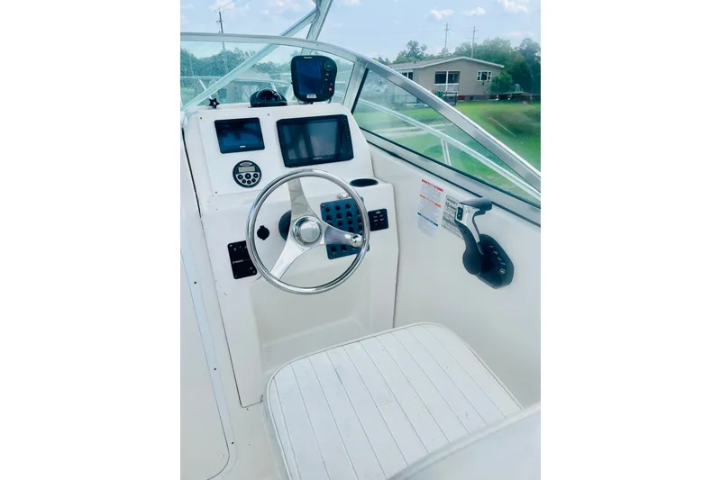 Slide: The Image of 2004 Robalo R235 Walkaround boat helm with steering wheel and navigation controls. - 6