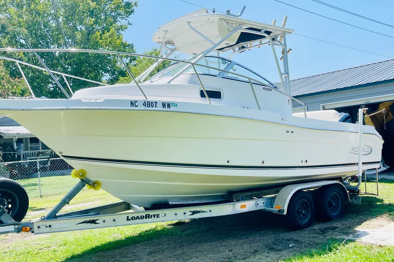 Slide: The Image of 2004 Robalo R235 Walkaround boat on trailer, parked outdoors. - 2