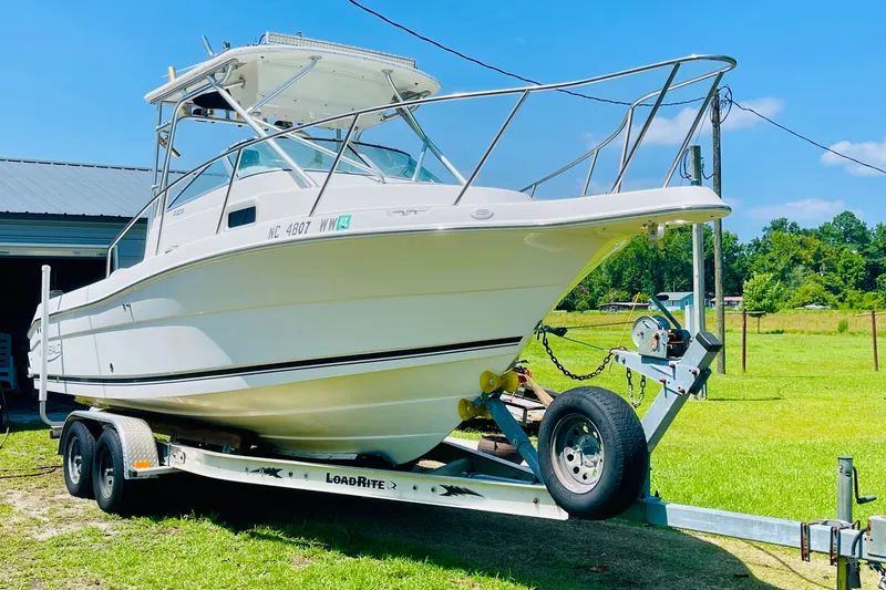 Slide: The Image of 2004 Robalo R235 Walkaround boat on trailer, parked outdoors on a sunny day. - 3