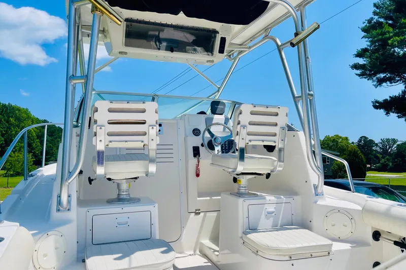 Slide: The Image of 2004 Robalo R235 Walkaround boat cockpit with dual seats and steering wheel under clear blue sky. - 4