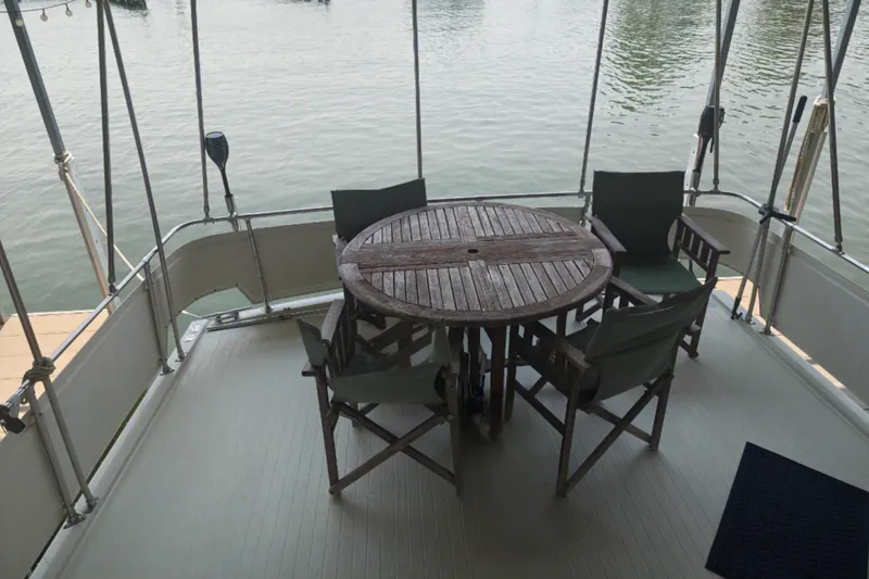 Slide: The Image of A round wooden table with four chairs on a boat deck by the water. - 8