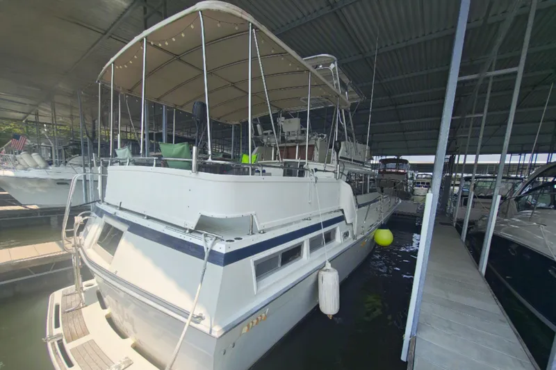 Slide: The Image of A white boat with a blue stripe is docked under a covered marina. - 6