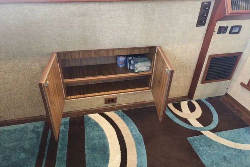 Slide: The Image of An open wooden cabinet with shelves and some items inside, on a patterned carpet. - 16