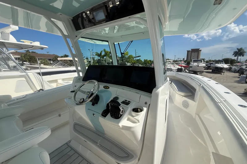 Slide: The Image of 2019 HCB 42 Siesta boat cockpit with modern controls and steering wheel, docked under clear skies. - 25