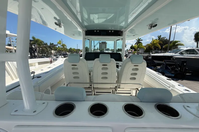 Slide: The Image of 2019 HCB 42 Siesta boat interior with seating and cup holders, docked under a clear sky. - 11