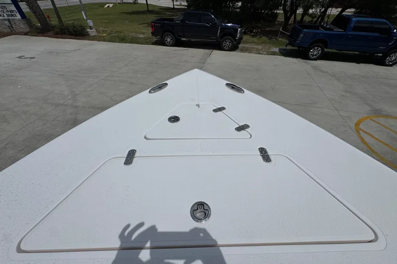 Slide: The Image of Bow view of 2024 Fountain 34 Tournament Edition boat, parked with trucks nearby. - 24