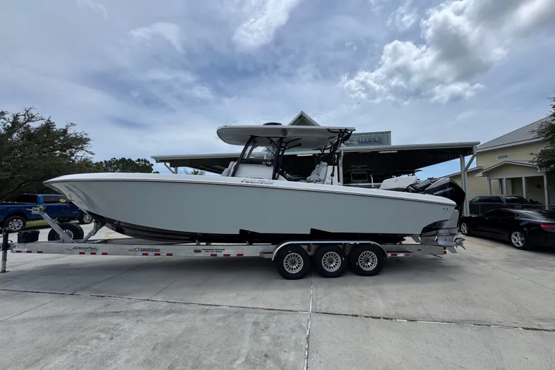 The Image of 2024 Fountain 34 Tournament Edition boat on trailer, parked outdoors under cloudy sky. - 1