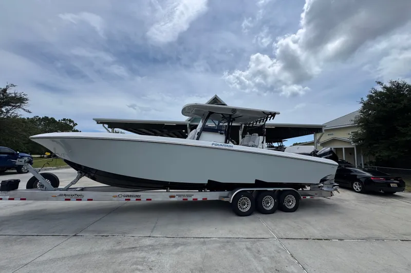 Slide: The Image of 2024 Fountain 34 Tournament Edition boat on trailer, parked outdoors under cloudy sky. - 2
