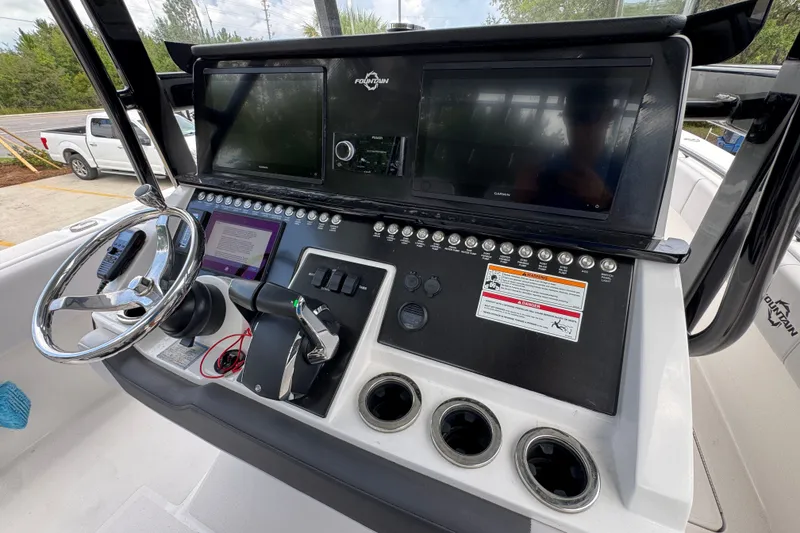 Slide: The Image of 2024 Fountain 34 Tournament Edition boat dashboard with steering wheel and control panel. - 38