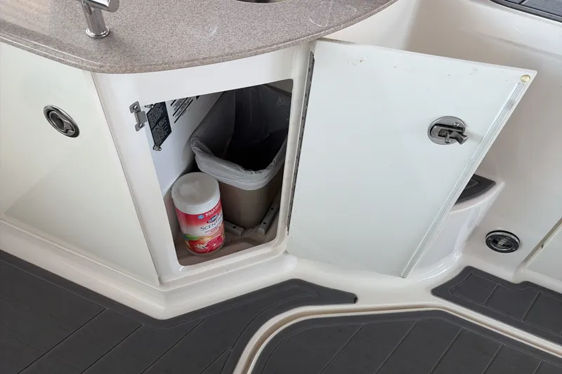 Slide: The Image of Open cabinet on 2007 Sea Ray 290 Sundancer boat, revealing trash bin and cleaning supplies. - 15
