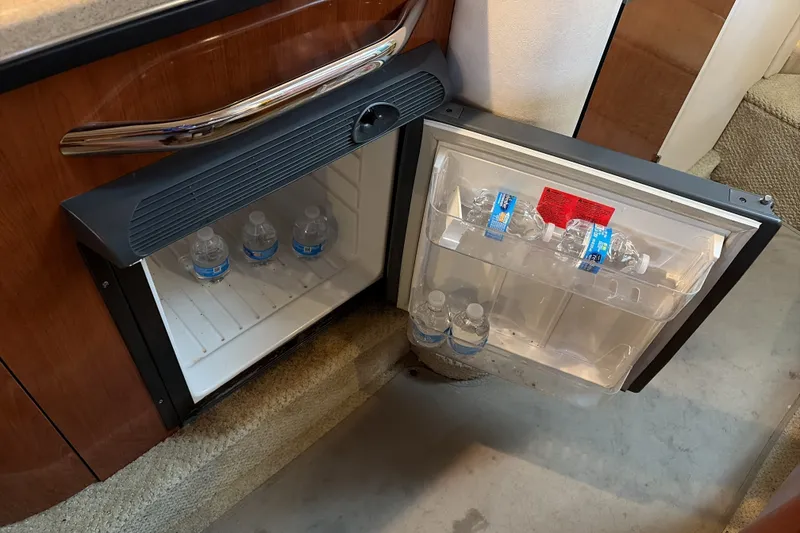 Slide: The Image of Mini fridge with water bottles inside a 2007 Sea Ray 290 Sundancer boat cabin. - 32