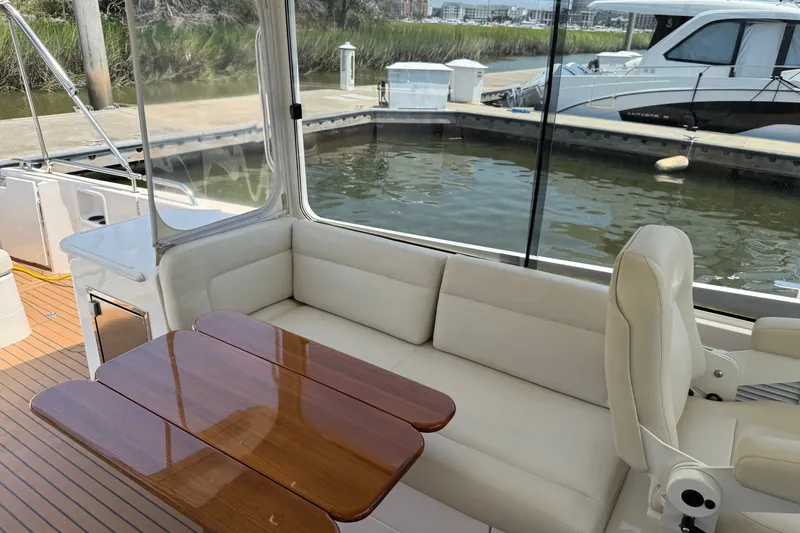 Slide: The Image of Interior of 2018 MJM 35z yacht with white seating and wooden table by the dock. - 16