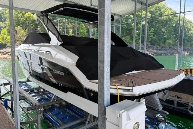 Slide: The Image of 2015 Cruisers Sport Series 328 boat docked on a lift, covered, with scenic lake backdrop. - 26