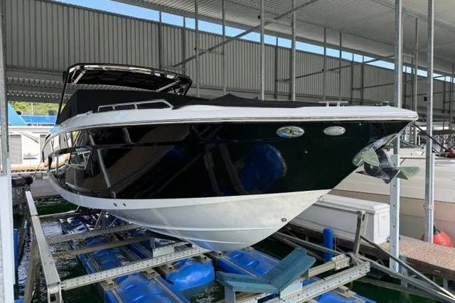 Slide: The Image of 2015 Cruisers Sport Series 328 boat in storage, featuring sleek black and white design. - 23