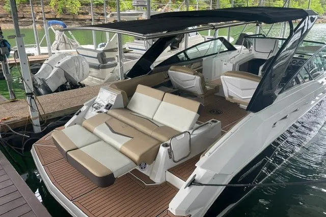 Slide: The Image of 2015 Cruisers Sport Series 328 boat with spacious deck and seating, docked in a marina. - 20