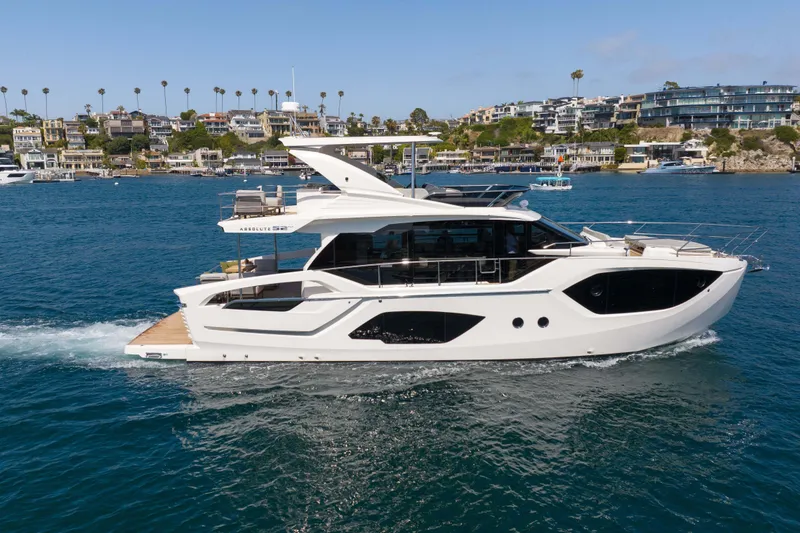Slide: The Image of Luxury Absolute 52 Fly yacht cruising near coastal homes, 2026 model. - 5