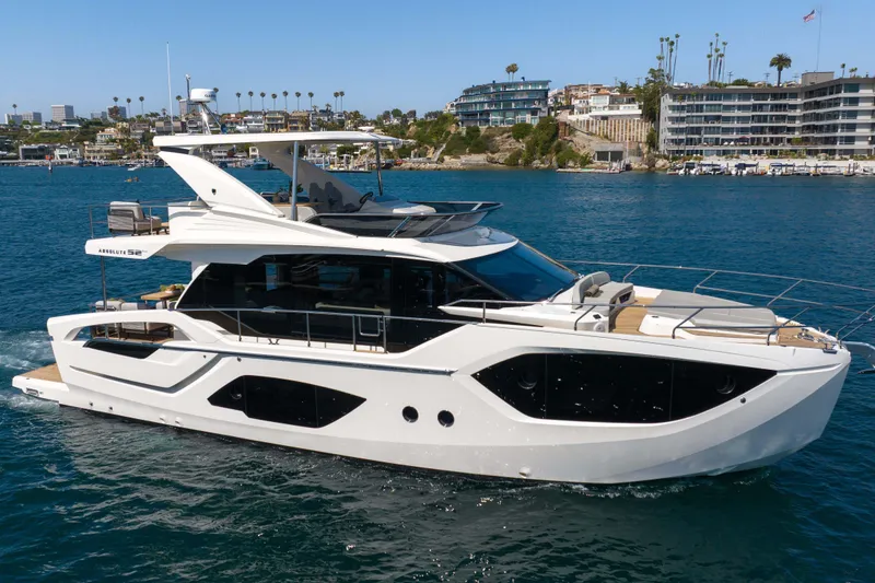 Slide: The Image of Luxurious 2026 Absolute 52 Fly yacht cruising near a scenic coastal cityscape. - 1