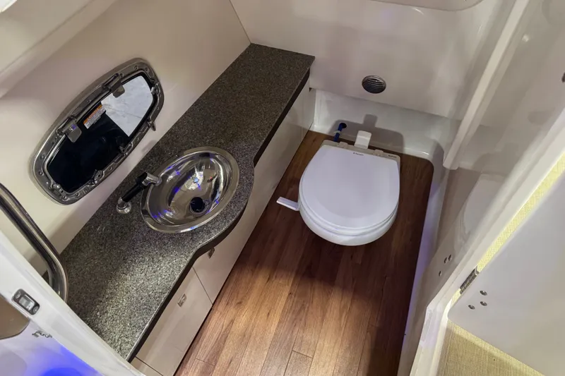 Slide: The Image of 2016 Chaparral 307 SSX boat bathroom with sink, toilet, and wood flooring. - 11