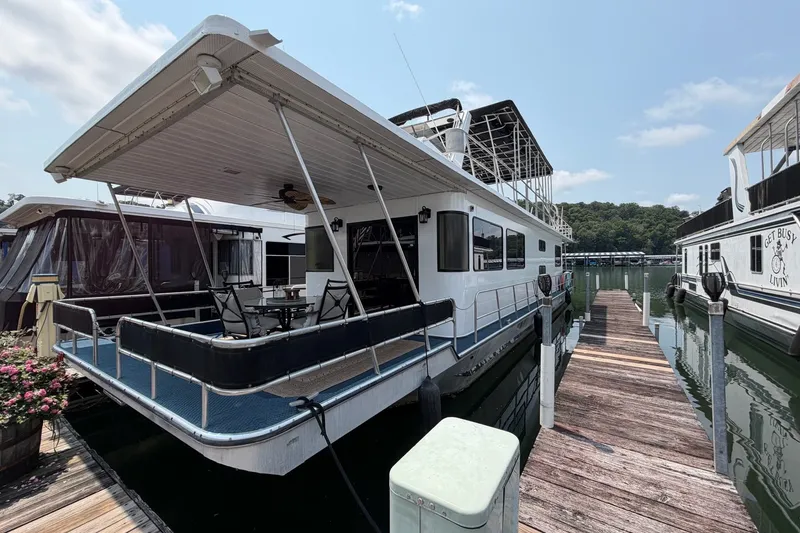 The Image of Houseboat docked at marina, Leisure Time 14x63 model, 1991, with outdoor seating area. - 0