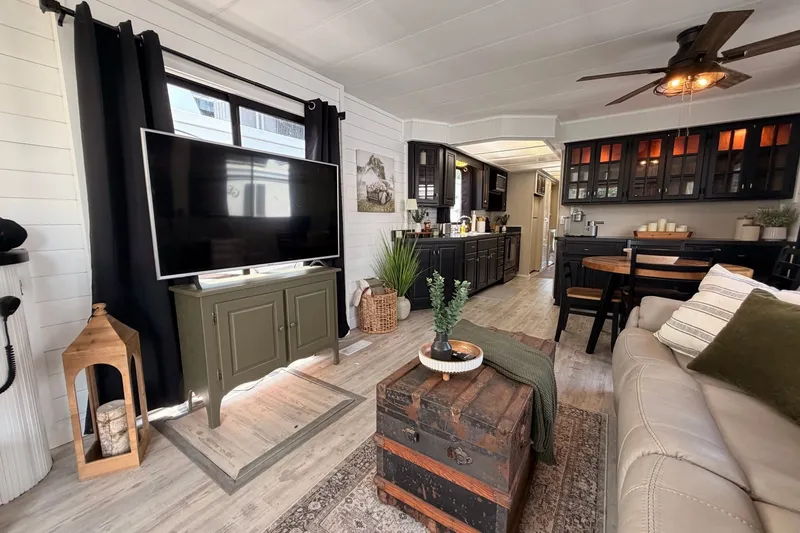 Slide: The Image of Cozy living area in a 1991 Leisure Time model, featuring modern decor and a large TV. - 20