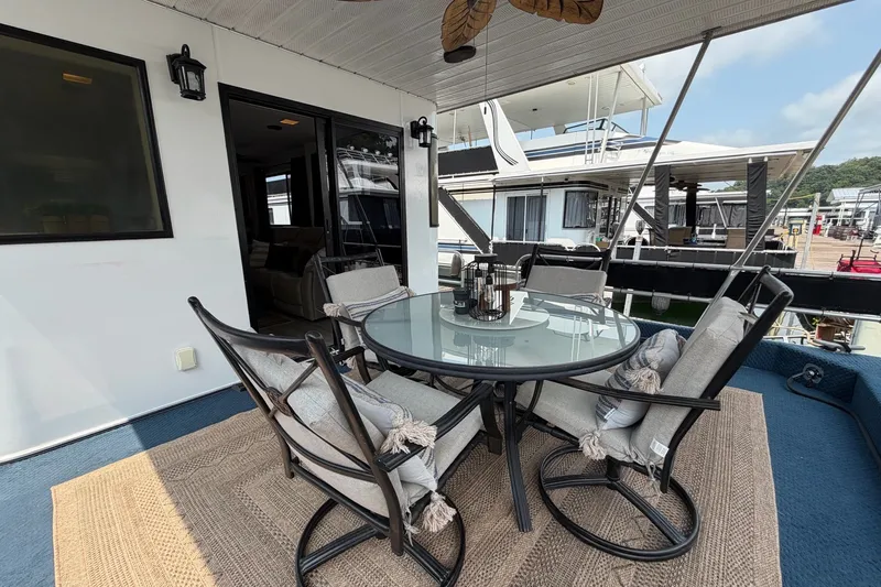 Slide: The Image of Outdoor seating area on a 1991 Leisure Time 14x63 houseboat, featuring a glass table and cushioned chairs. - 10