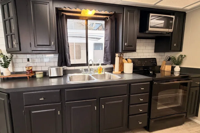 Slide: The Image of Modern kitchen with black cabinets, stainless steel sink, and appliances in a 1991 Leisure Time model. - 23