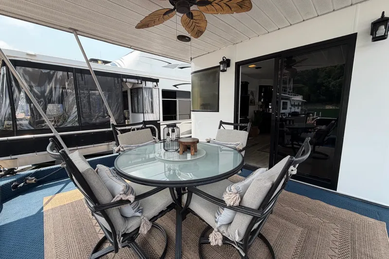 Slide: The Image of Outdoor dining area on a 1991 Leisure Time 14x63 houseboat with glass table and cushioned chairs. - 9