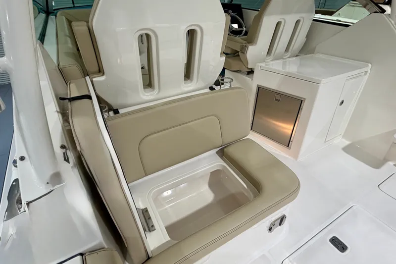 Slide: The Image of 2019 Pursuit DC 325 Dual Console interior with beige seating and storage compartment. - 30