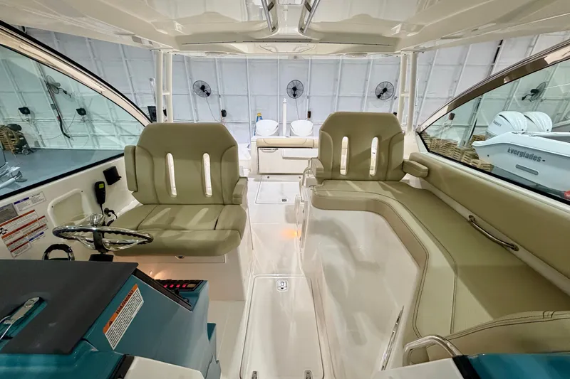 Slide: The Image of 2019 Pursuit DC 325 Dual Console interior with beige seating and modern helm. - 22
