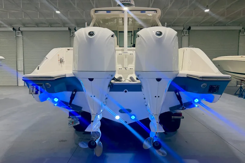 Slide: The Image of 2019 Pursuit DC 325 Dual Console boat with dual engines and blue LED lights in a showroom. - 42