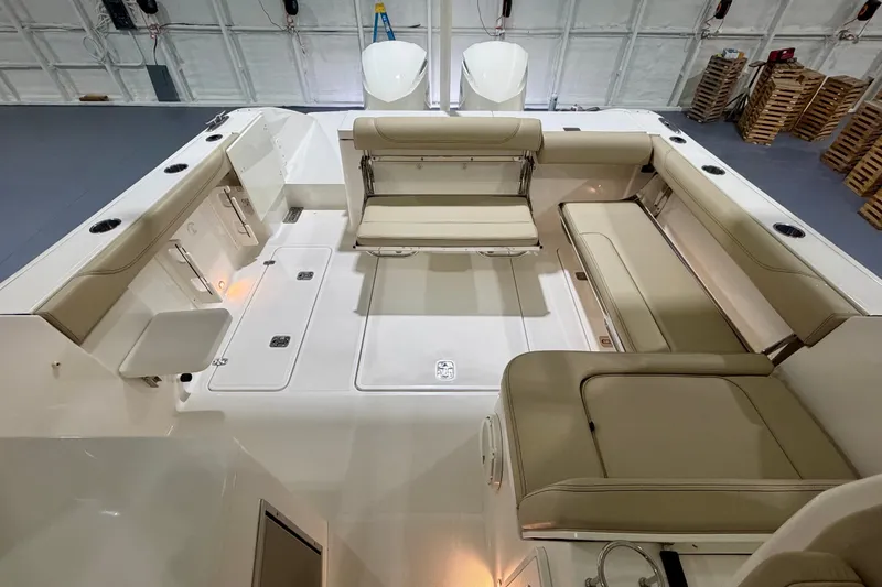 Slide: The Image of 2019 Pursuit DC 325 Dual Console boat interior with beige seating and storage compartments. - 20