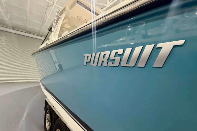 Slide: The Image of 2019 Pursuit DC 325 Dual Console boat in a showroom, showcasing sleek design. - 13