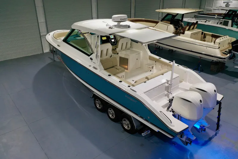 The Image of 2019 Pursuit DC 325 Dual Console boat in showroom, featuring twin engines and sleek design. - 0