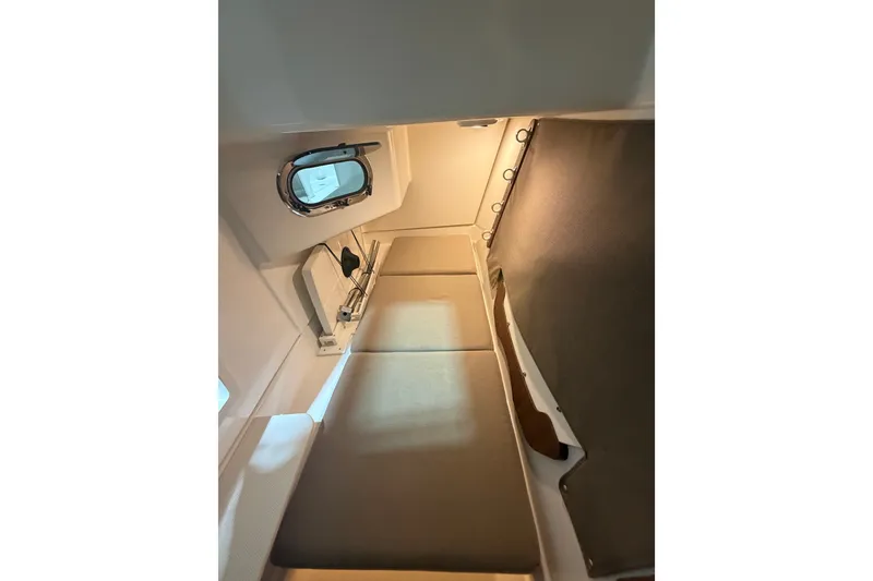 Slide: The Image of Interior cabin of 2019 Pursuit DC 325 Dual Console boat, featuring cozy seating and porthole. - 33