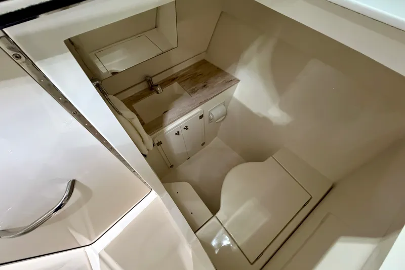 Slide: The Image of 2019 Pursuit DC 325 Dual Console boat interior with compact bathroom and sink. - 36