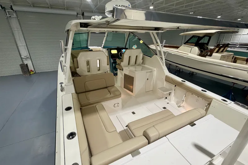 Slide: The Image of 2019 Pursuit DC 325 Dual Console boat interior with beige seating in a showroom. - 19