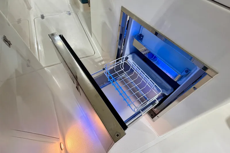 Slide: The Image of Open drawer refrigerator on 2019 Pursuit DC 325 Dual Console boat, featuring blue LED lighting. - 29