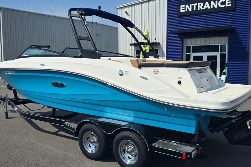 Slide: The Image of 2024 Sea Ray SPX 230 boat with blue hull on trailer, parked outside dealership. - 2