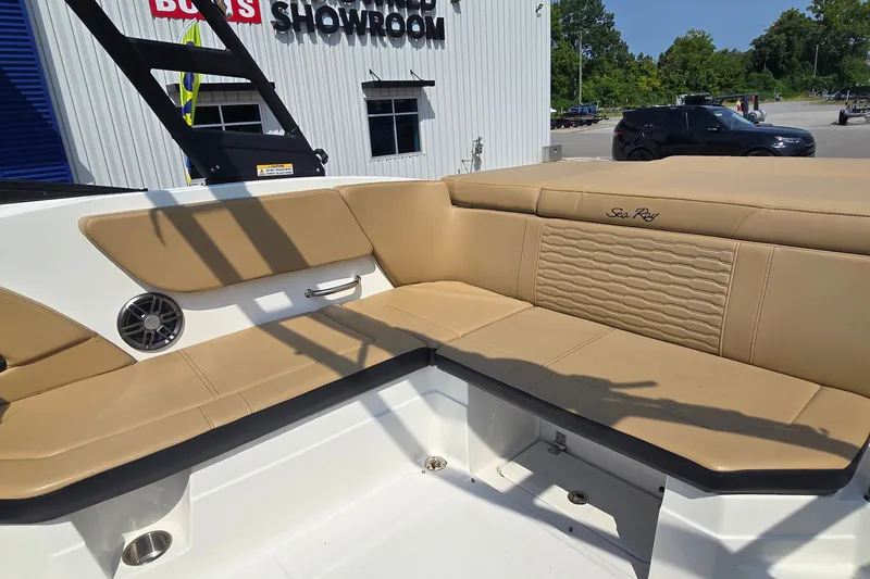Slide: The Image of 2024 Sea Ray SPX 230 boat interior with tan seating and speaker, showroom background. - 9