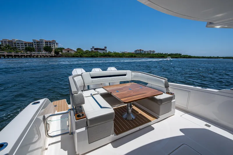 Slide: The Image of 2024 Tiara Yachts 38 LS luxury yacht deck with seating and table, overlooking scenic waterfront. - 25