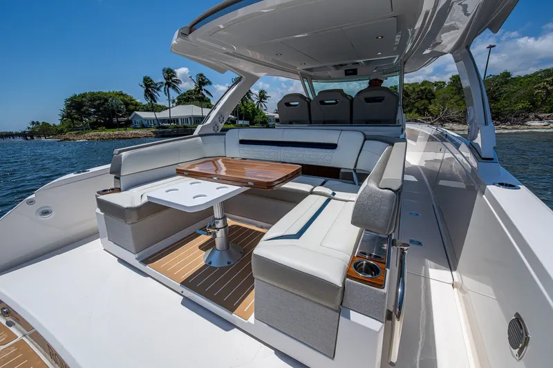 Slide: The Image of 2024 Tiara Yachts 38 LS luxury boat interior with seating and table, docked by palm trees. - 27
