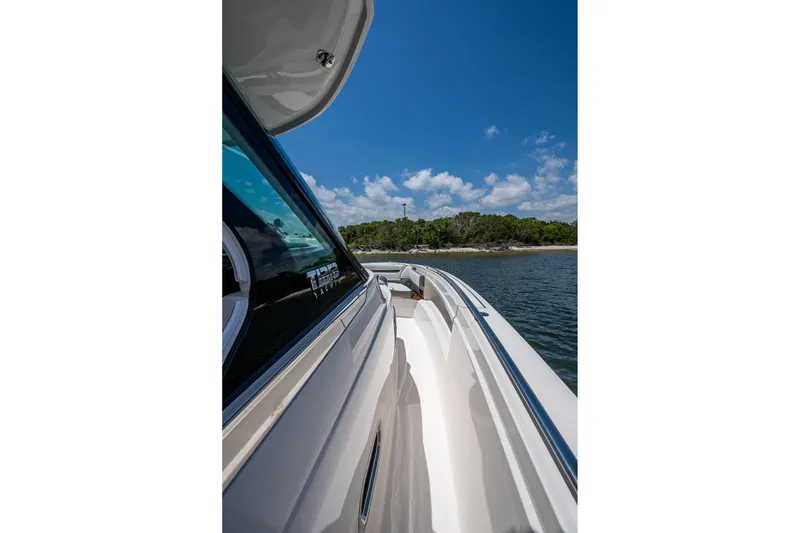 Slide: The Image of 2024 Tiara Yachts 38 LS cruising near a scenic shoreline under a clear blue sky. - 22